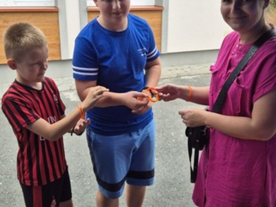 1)	Na fotografii pracownica Miejsko – Gminnego Ośrodka Pomocy Społecznej w Sompolnie podczas pikniku rodzinnego który odbył się w Sycewie. Rozdaje dzieciom opaski silikonowe z nadrukiem „Stop przemocy!”