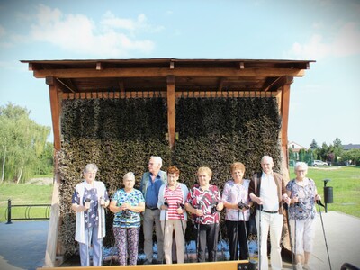 Zdjęcie grupowe przedstawiające Seniorów stojących przy tężni solankowej