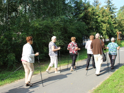 Zdjęcie przedstawia seniorów  spacerujących po ścieżce.