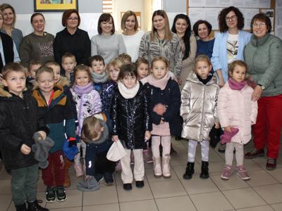 Zdjęcie grupowe przedstawia pracowników socjalnych wraz z dziećmi z przedszkola.