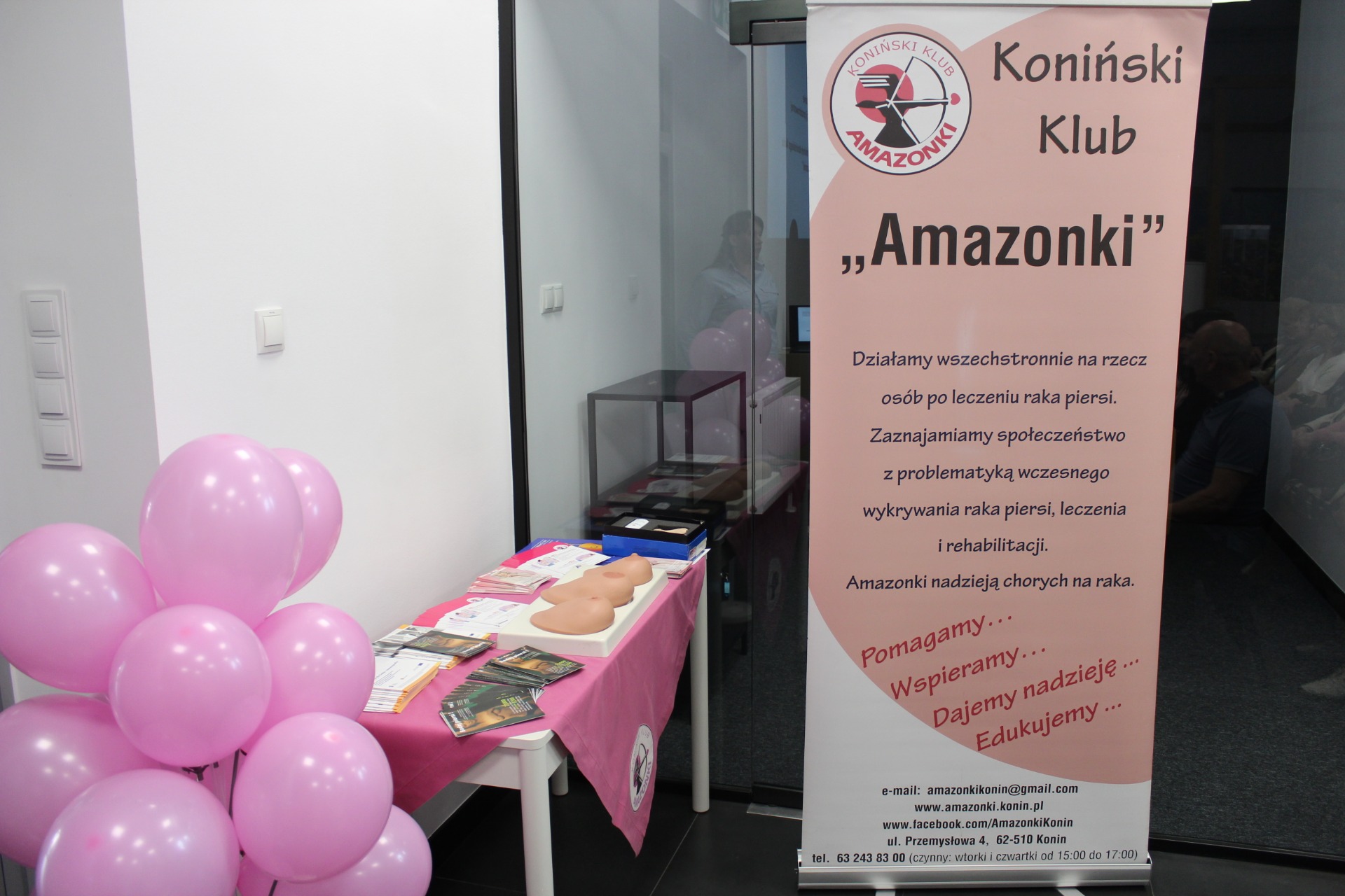 1. Zdjęcie przedstawia baner oraz ułożone na stoliku materiały edukacyjne przygotowane przez Koniński Klub „Amazonki” na potrzeby spotkania