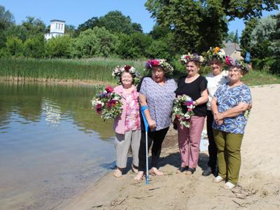 Grupa seniorek nad Jeziorem Lubstowskim. Po lewej stronie woda, po prawej plaża, w tle zieleń i fragment pałacu.