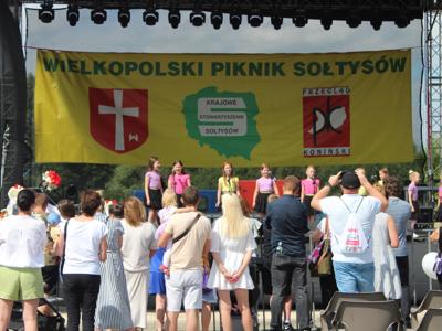 Fotografia przedstawia scenę, publiczność oraz młodych artystów podczas XXV Wielkopolskiego Pikniku Sołtysów.