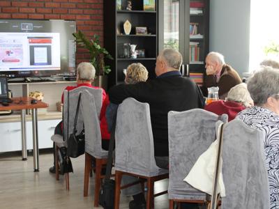 Na zdjęciu seniorzy słuchający webinarium o cyberbezpieczeństwie