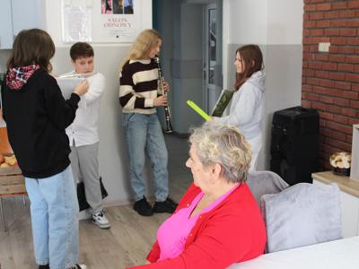 Zdjęcie wykonane w domu sali głównej Domu Dziennego Pobytu – przedstawia dzieci grające na instrumentach