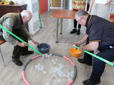 2) Zdjęcie przedstawia dwóch Panow – uczestników DDP konkurujących ze sobą podczas zabawy ruchowej.