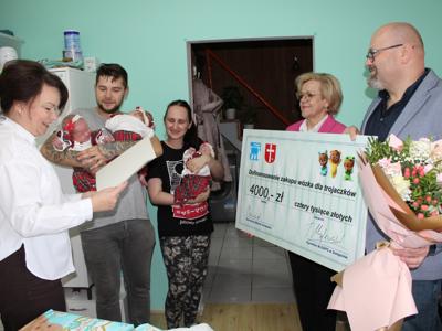 1) Zdjęcie wykonane w domu rodziców trojaczków. Przedstawia rodziców, dzieci oraz przedstawicieli urzędu.