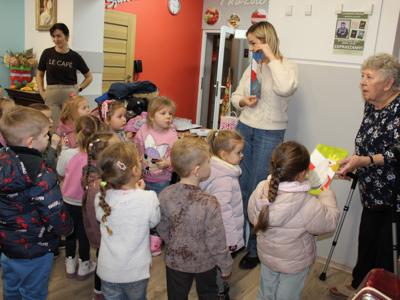 6. Na zdjęciu Pani przedszkolanka przedstawia dzieciom prace plastyczne wykonane przez seniorów